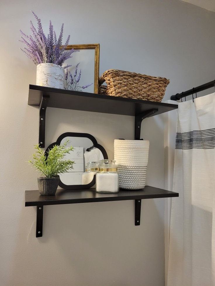 Dark wood bathroom shelves styled with a woven basket, lavender stems, a mirror and glass apothecary jars