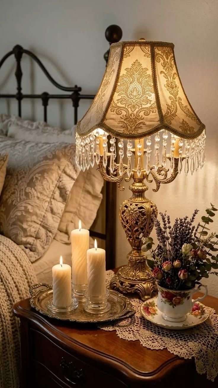 Vintage beaded lamp glowing warm light beside lit pillar candles and a teacup of dried lavender on a wood nightstand