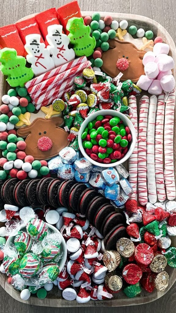 Christmas dessert board with reindeer and snowman cookies, candy canes, red and green M&Ms, Oreos and foil-wrapped chocolate kisses