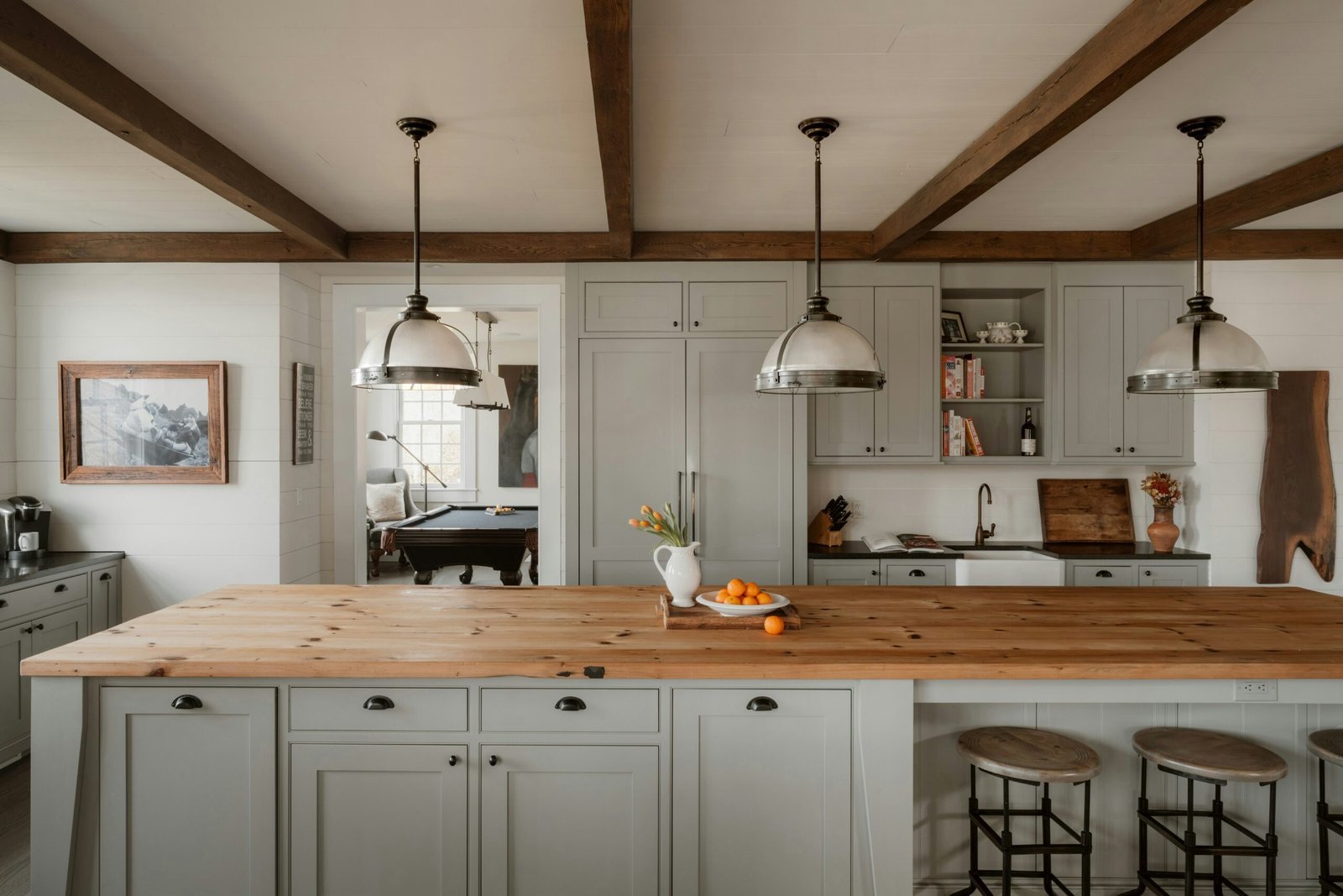 Farmhouse kitchen with exposed beams, a butcher block island and vintage pendant lights