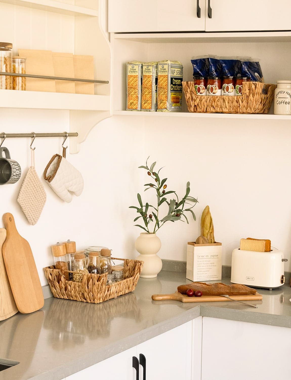 Woven tray holding small spice jars and a wooden bowl on a kitchen shelf