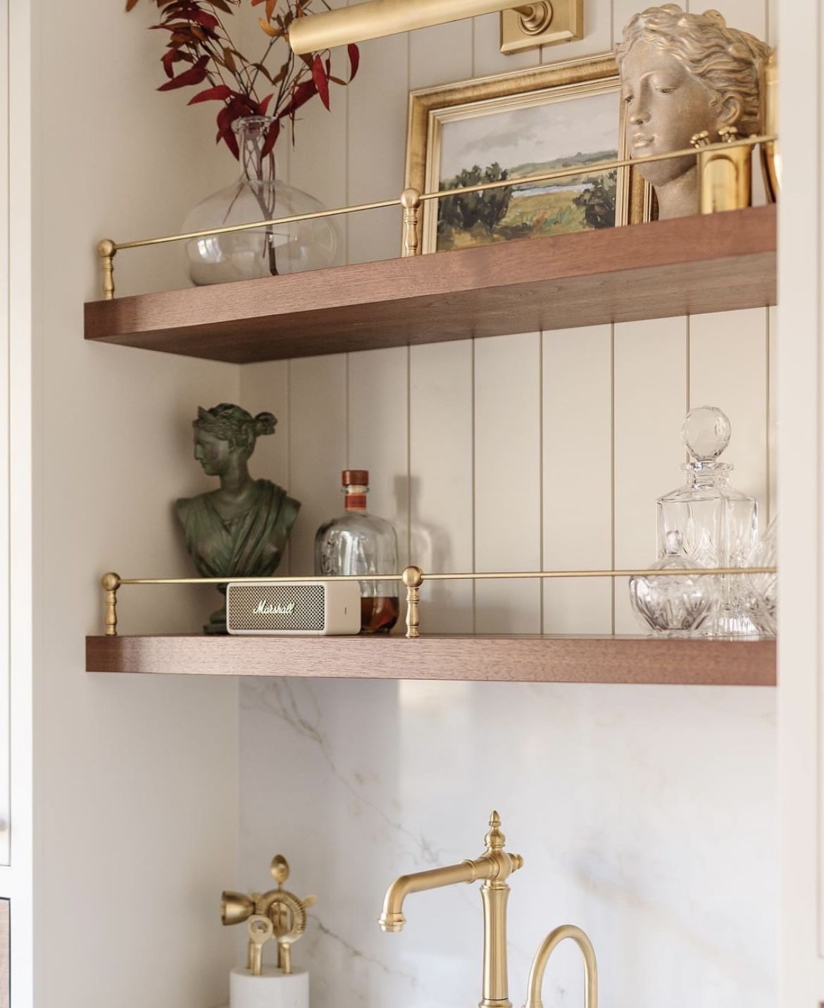 Elegant brass-railed shelves styled with classical busts, decanters and framed art
