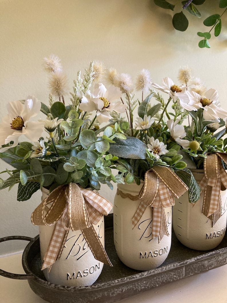 Farmhouse-style Mason jar centerpiece wrapped with a bow on a dining table
