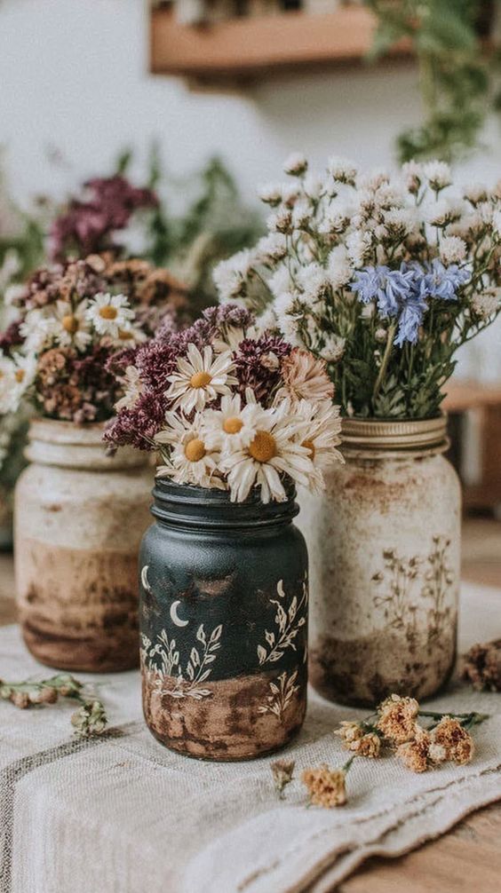 Painted Mason jars in muted tones filled with dried flowers, styled together
