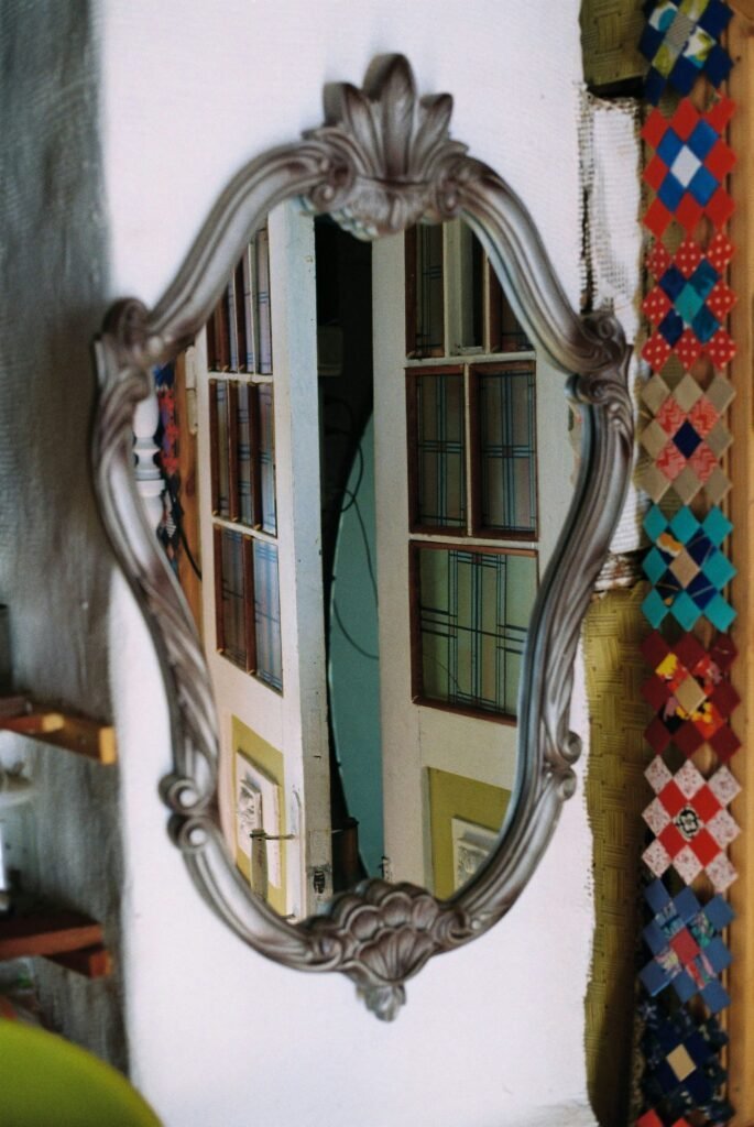 Ornate scalloped-frame mirror with bevelled glass edges catching light near a window
