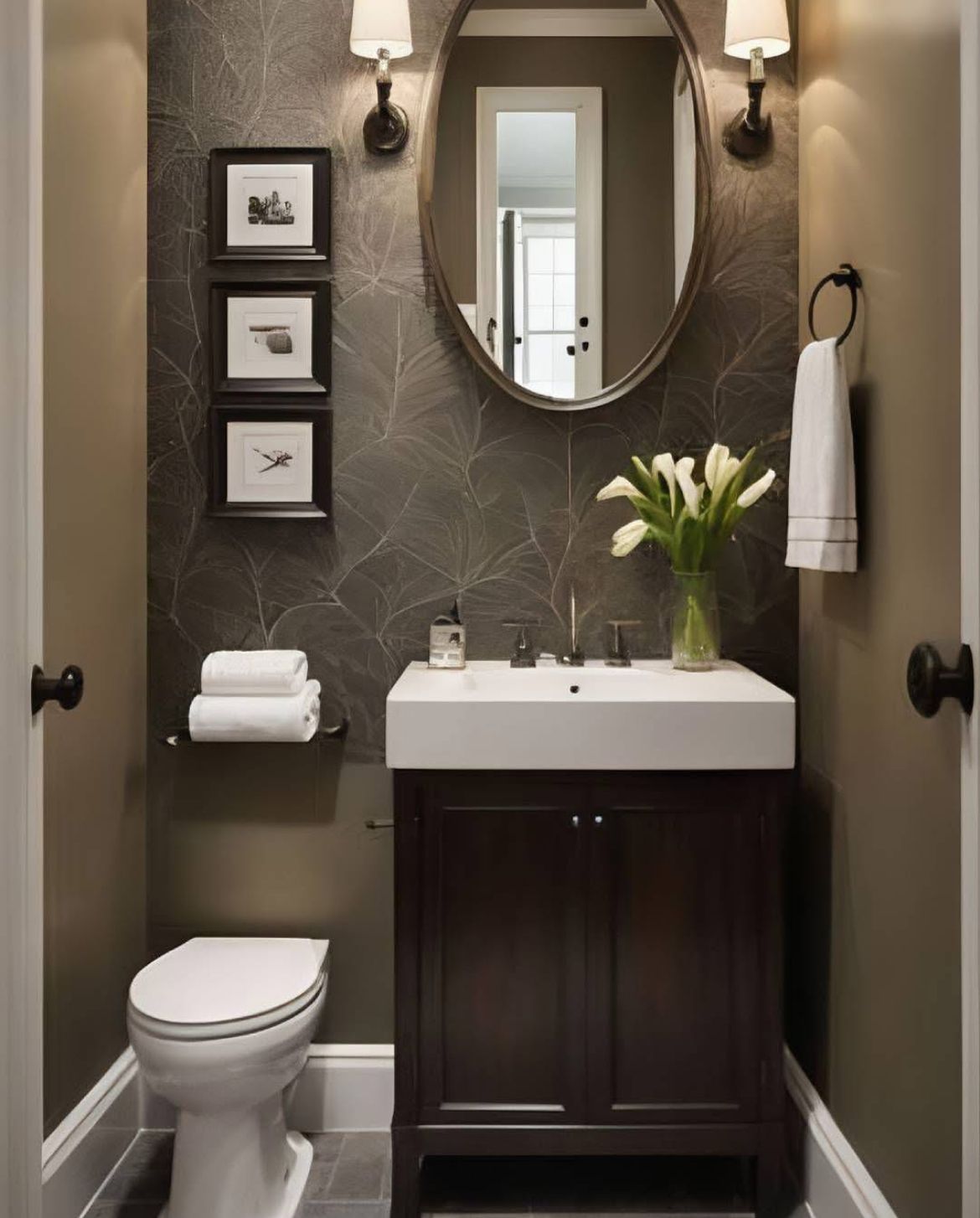 Styled powder room counter with a small plant, fresh flowers, a candle and rolled towels beside a vessel sink