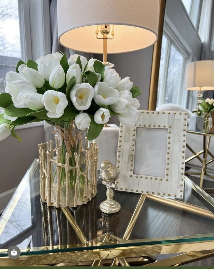 White tulips in a vase styled on a glass side table with a framed photo