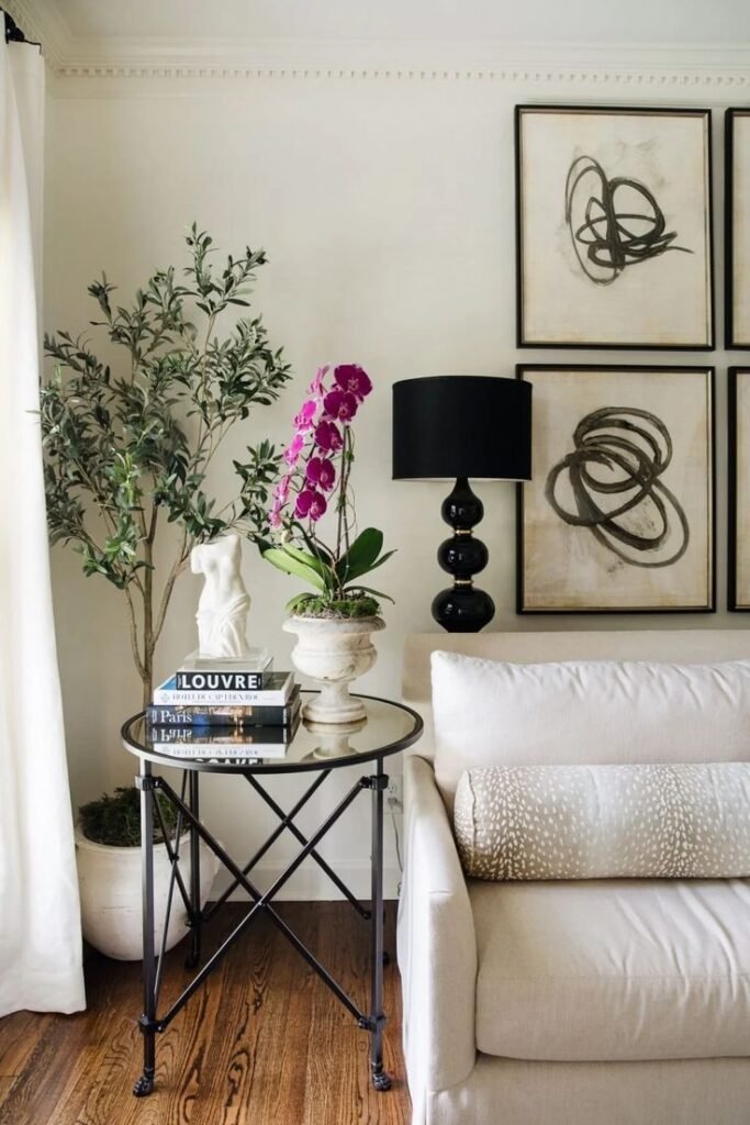 Round side table styled with books, an orchid and a black table lamp