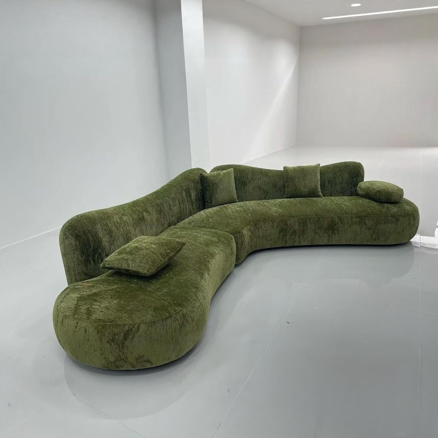 Olive green sculptural curved sofa with an architectural silhouette