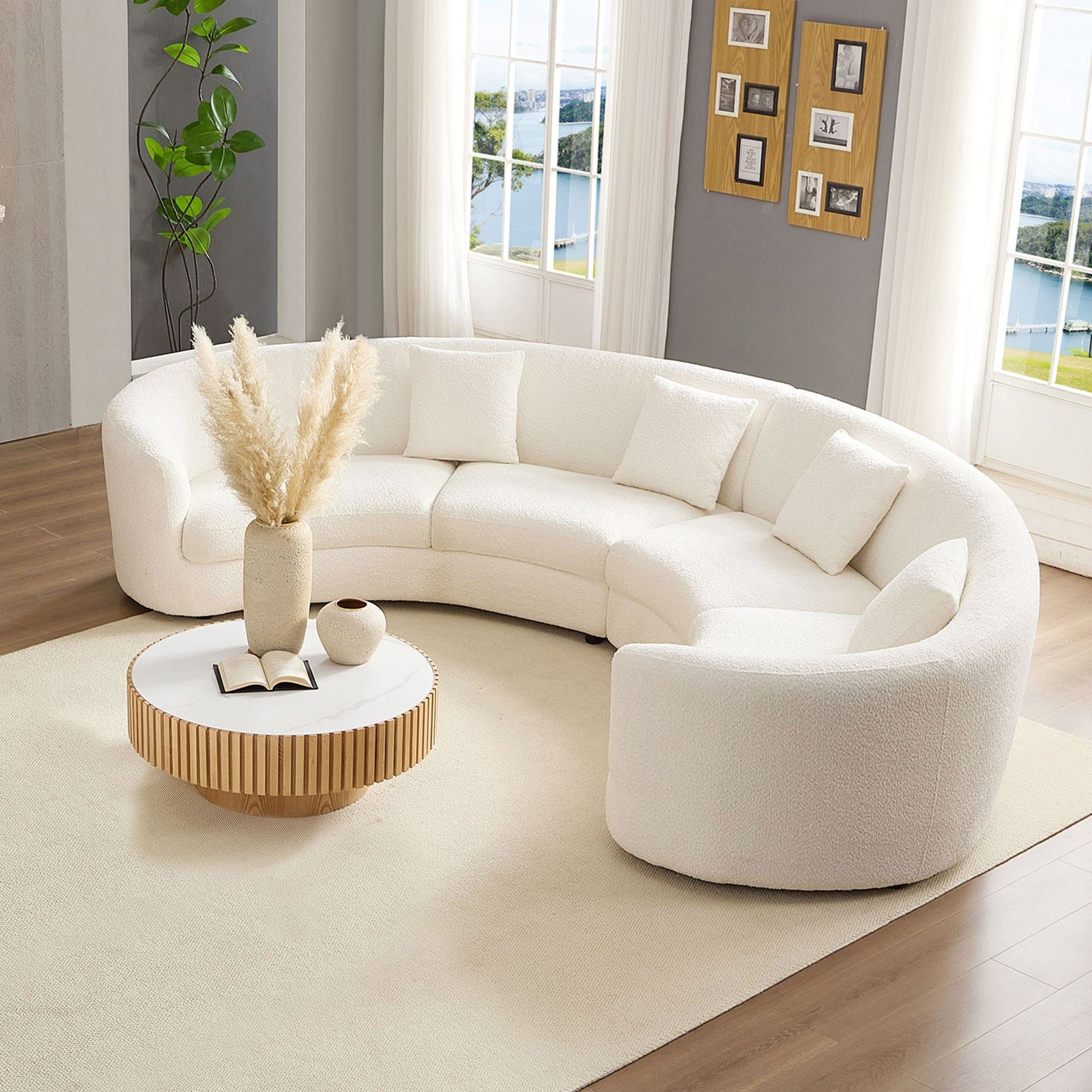 Half-circle cream bouclé sofa wrapped around a round fluted wood coffee table with pampas grass