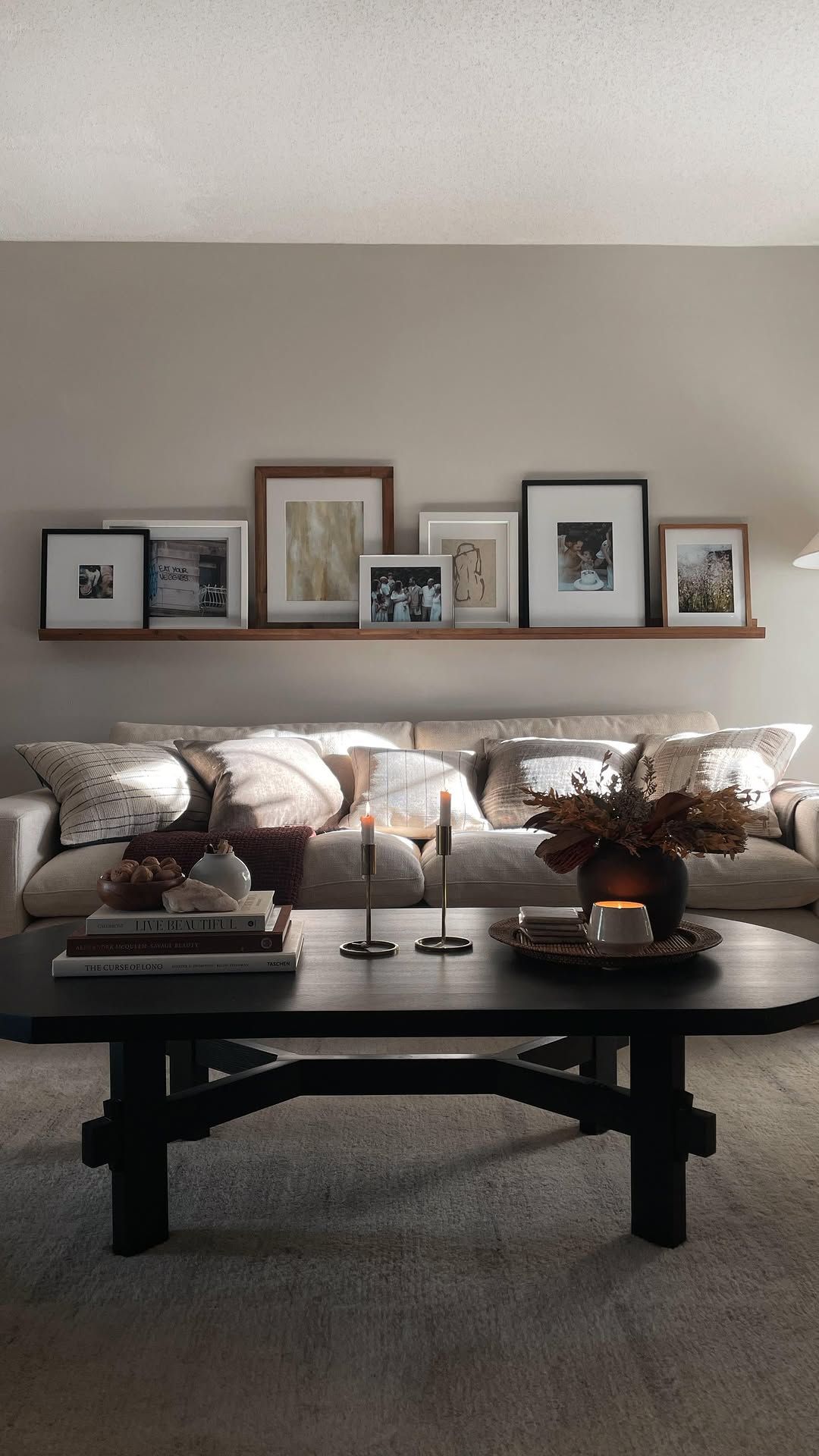 Long picture ledge layered with a mix of framed photographs and artwork above a sofa