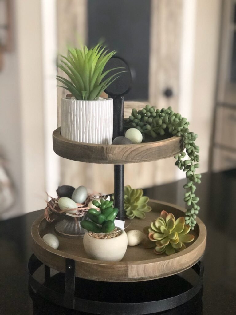 Tiered tray styled as a mini garden centerpiece with small plants and moss