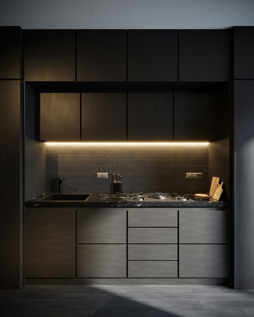 Sleek dark single-wall kitchen with a black marble countertop, built-in cooktop, under-cabinet lighting and a tile backsplash