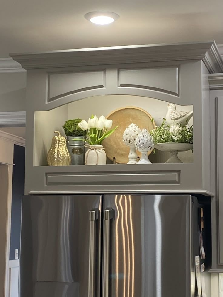 Built-in alcove above a fridge styled with neutral ceramic objects