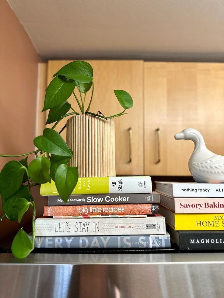 Stack of cookbooks and a small ceramic duck styled above a fridge