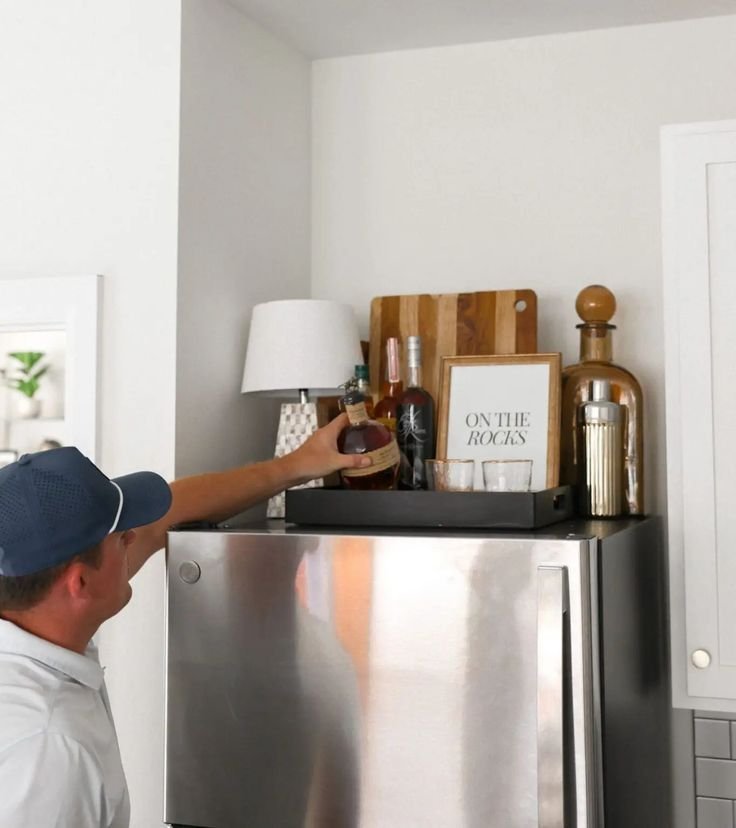 Wooden cutting boards and a bar tray styled above a refrigerator