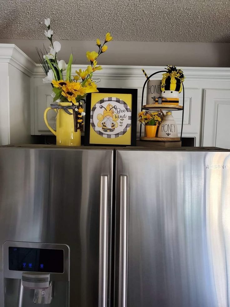 Large yellow decorative pitcher and framed sign styled on a fridge top