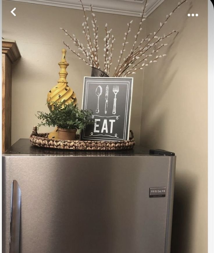 Styled top of fridge with a willow branch arrangement and an EAT sign