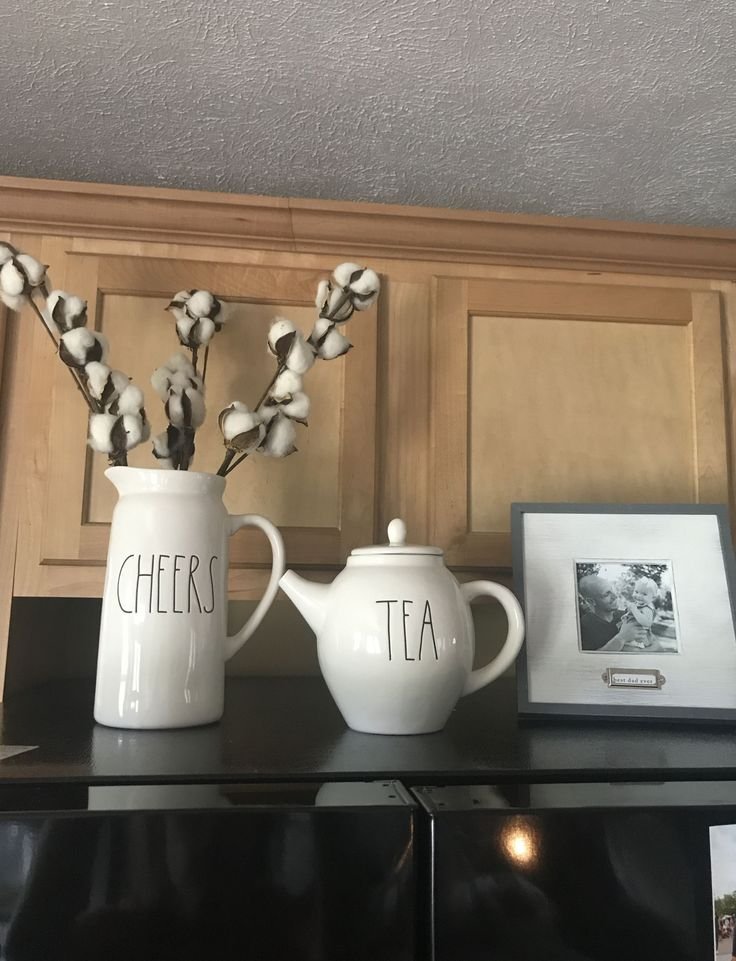 Matching ceramic pitcher and teapot styled above a black refrigerator