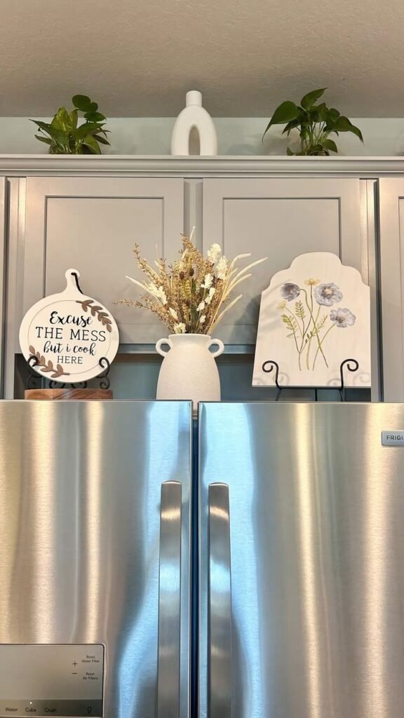Tall white vase and floral arrangement styled above a kitchen refrigerator