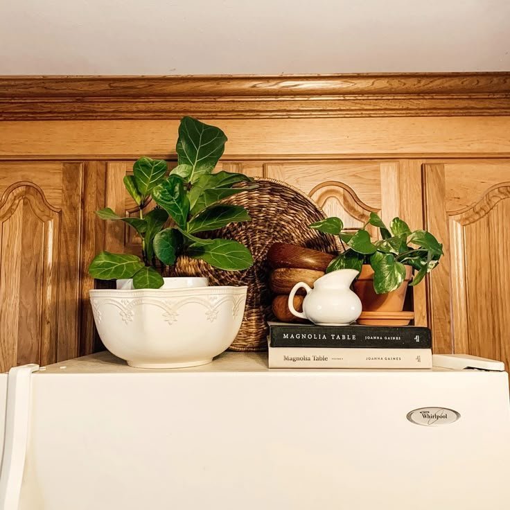 Woven tray, ceramic bowl and cookbooks styled above a wood-paneled fridge