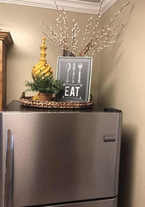 Vintage-style decor with a willow branch arrangement above a fridge
