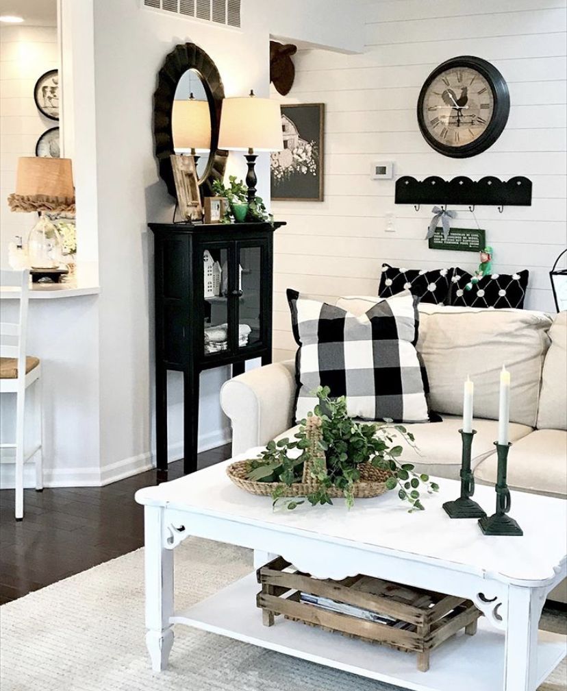 White farmhouse living room with a black accent cabinet, oval mirrors, black candlesticks and a buffalo check pillow